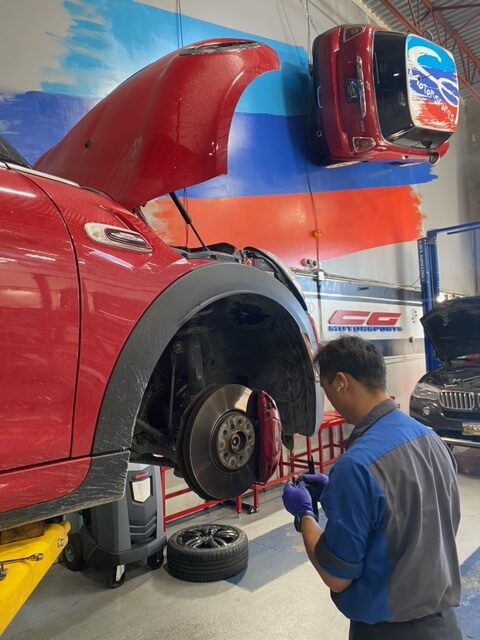 BMW Mini Technician examining a red BMW Mini in the at CG Motorsports